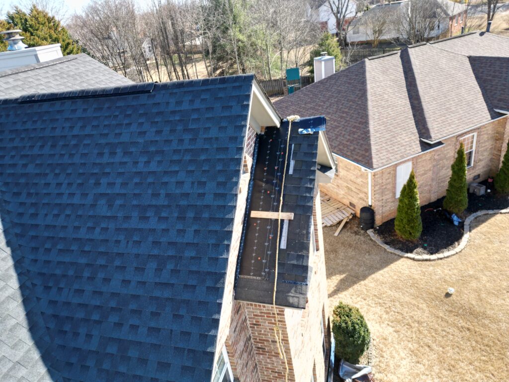 Residential roofing in progress on a blue shingle roof in Madison, showing underlayment and construction materials at a roof valley.